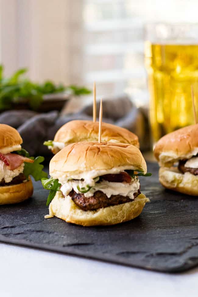 Bacon & Goat Cheese sliders with arugula and herb mayonnaise on a slate board