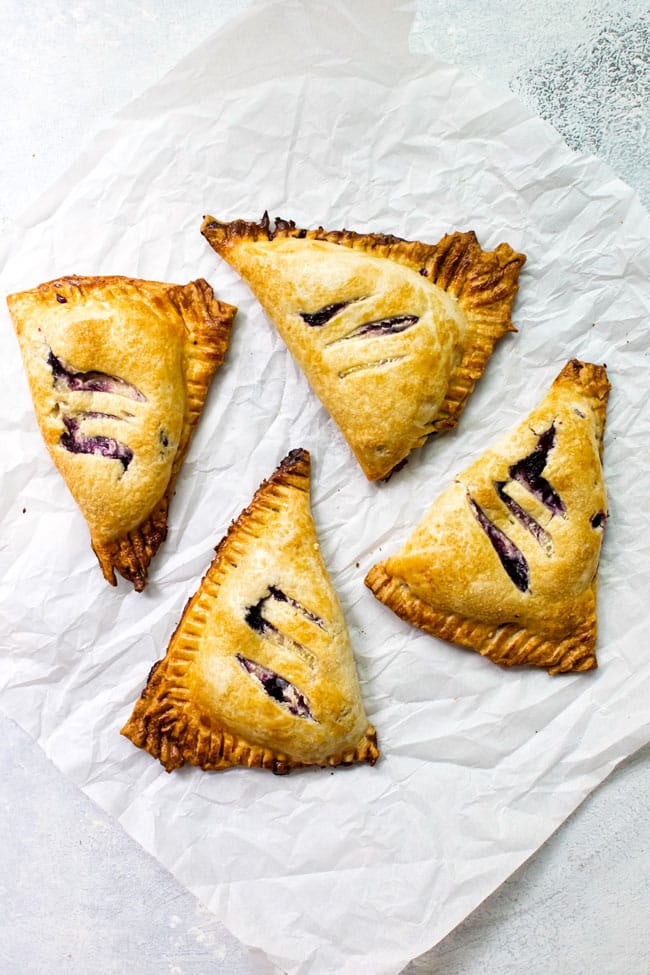 Four blueberry hand pies on parchment paper