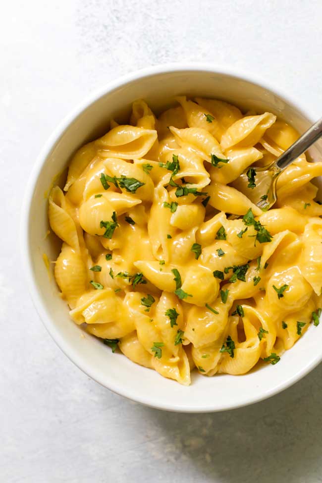 mac and cheese for one in a white bowl garnished with parsley