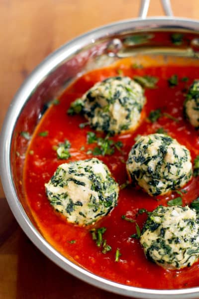 chicken and spinach meatballs in a skillet with tomato sauce