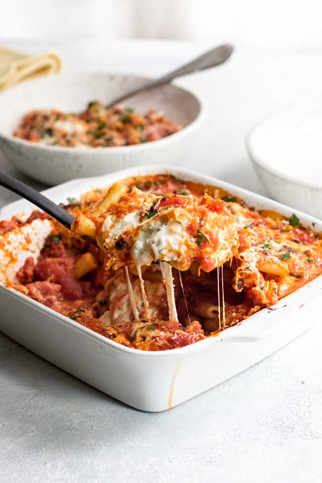 photo of a spoon lifting out cheesy baked ziti