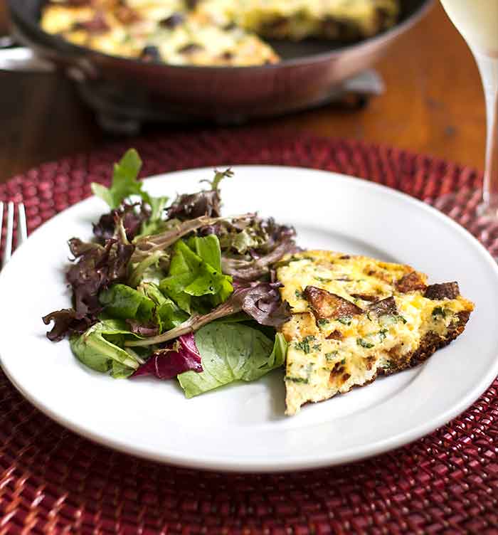 close-up photo of a slice of Chorizo Potato Frittata with a green salad on the side