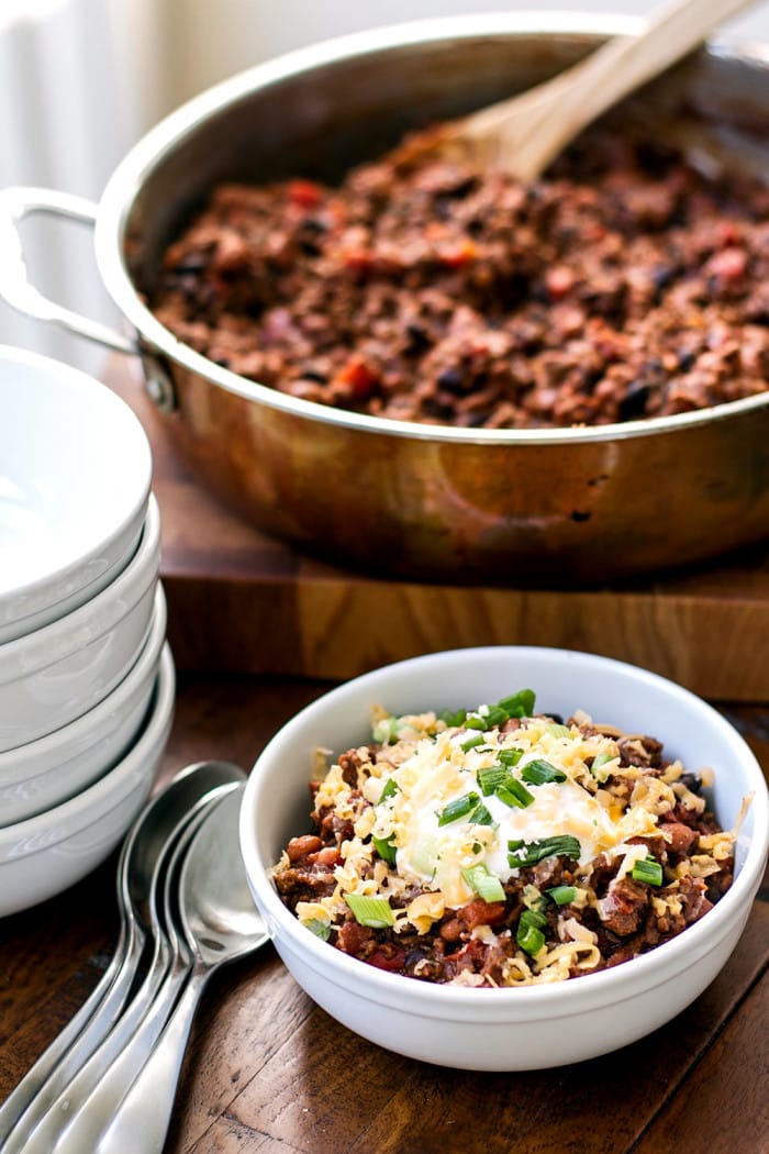 Easy ground beef chili in a bowl garnished with sour cream, cheese, and green onions