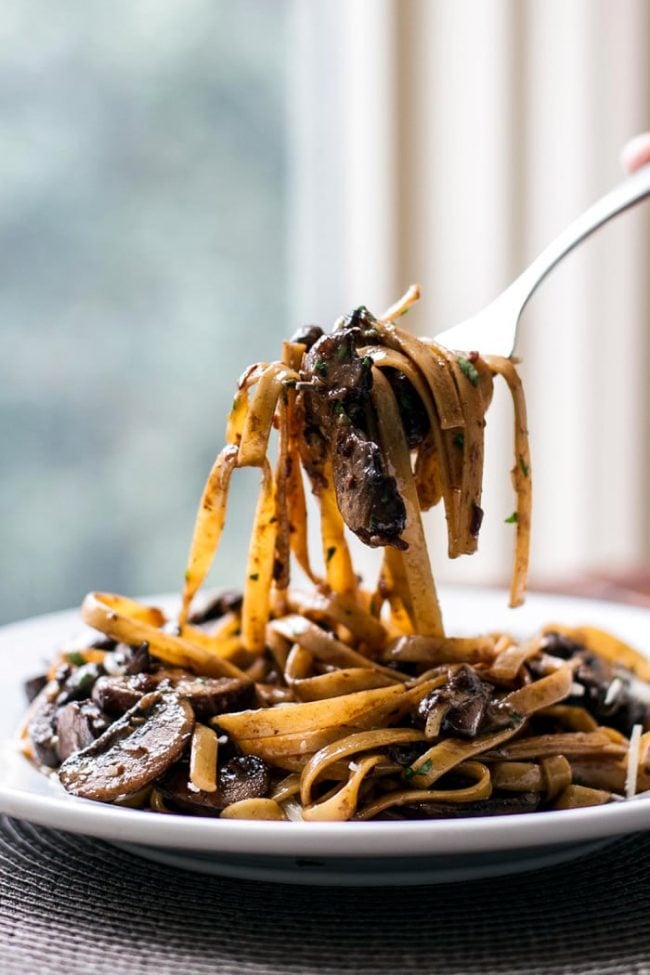 Balsamic mushroom pasta on a white plate with the pasta twirled onto a fork