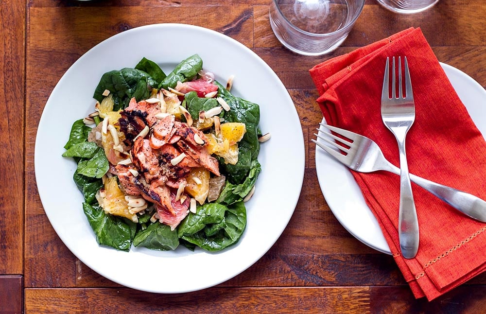 Salmon, citrus, and greens on a white plate