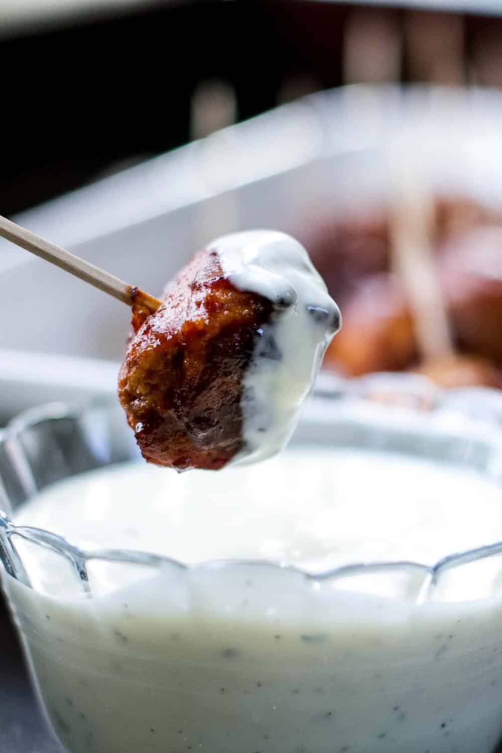One Honey BBQ Chicken Meatball on a toothpick dipped in ranch dressing