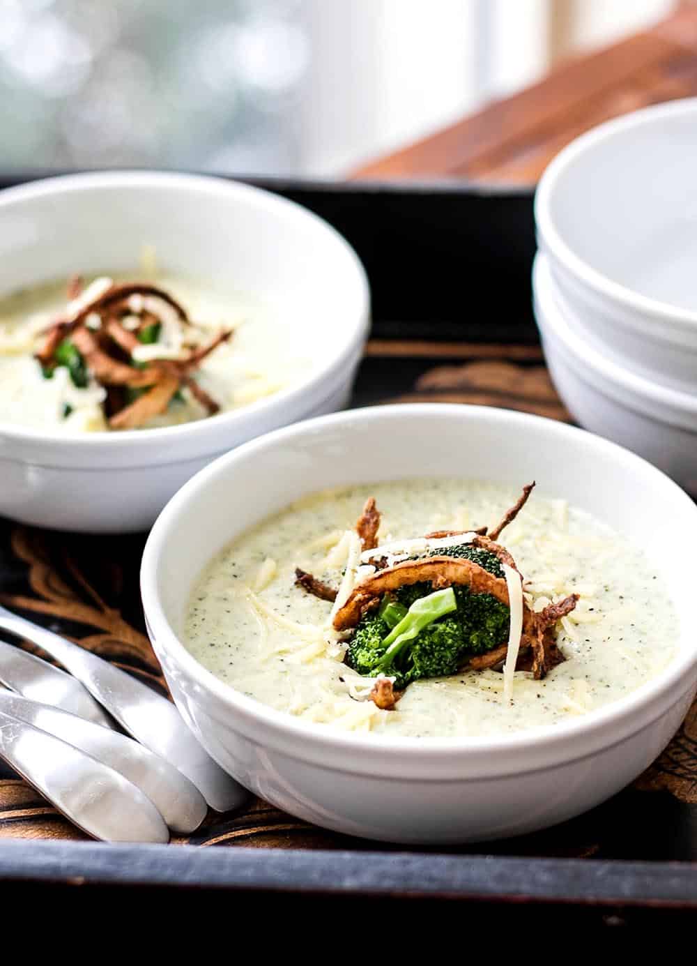 Two bowls of broccoli cheese soup on a tray