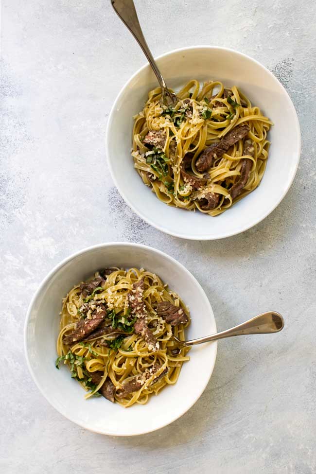 Two bowls of steak carbonara with forks