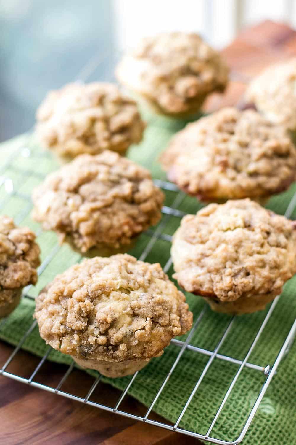 Banana nut muffins lined up on a bakers rack by a window