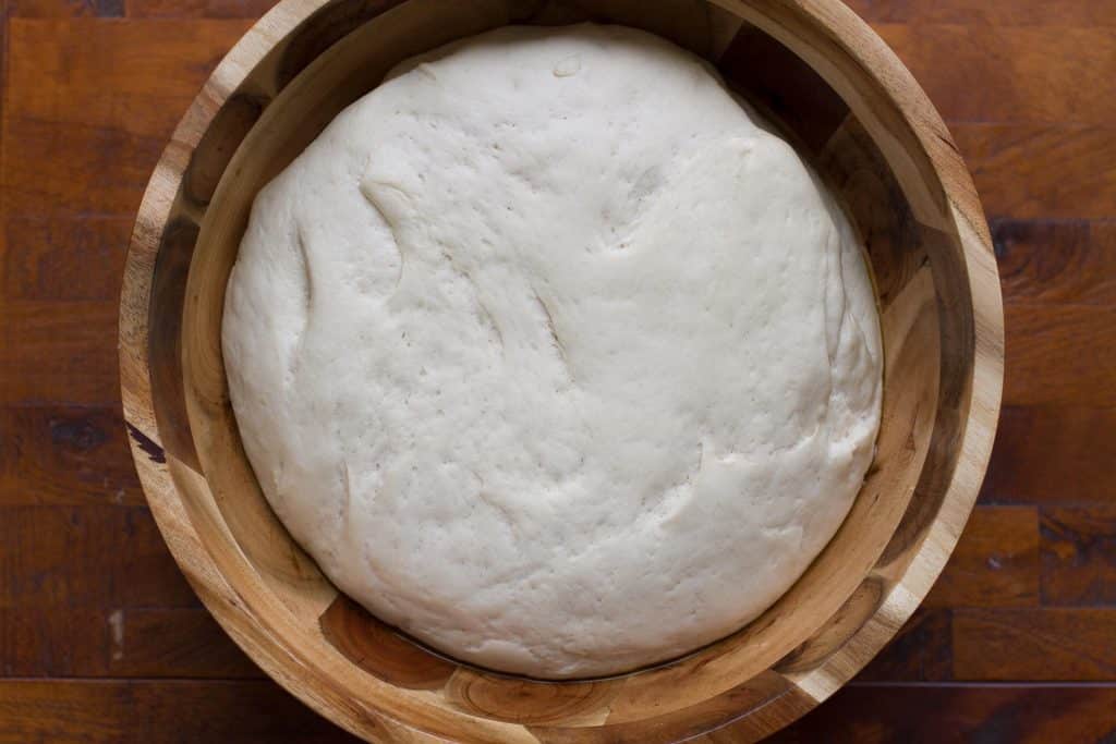 Foccacia dough in a wooden bowl after the first rise