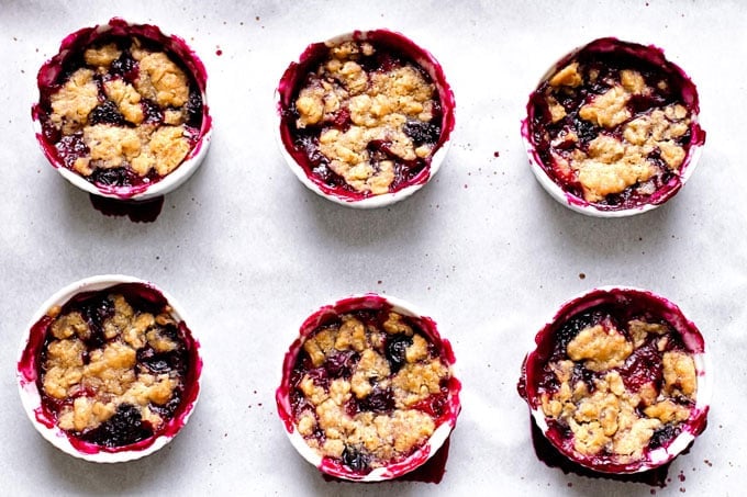 six berry crumbles on a sheet pan lined with parchment paper