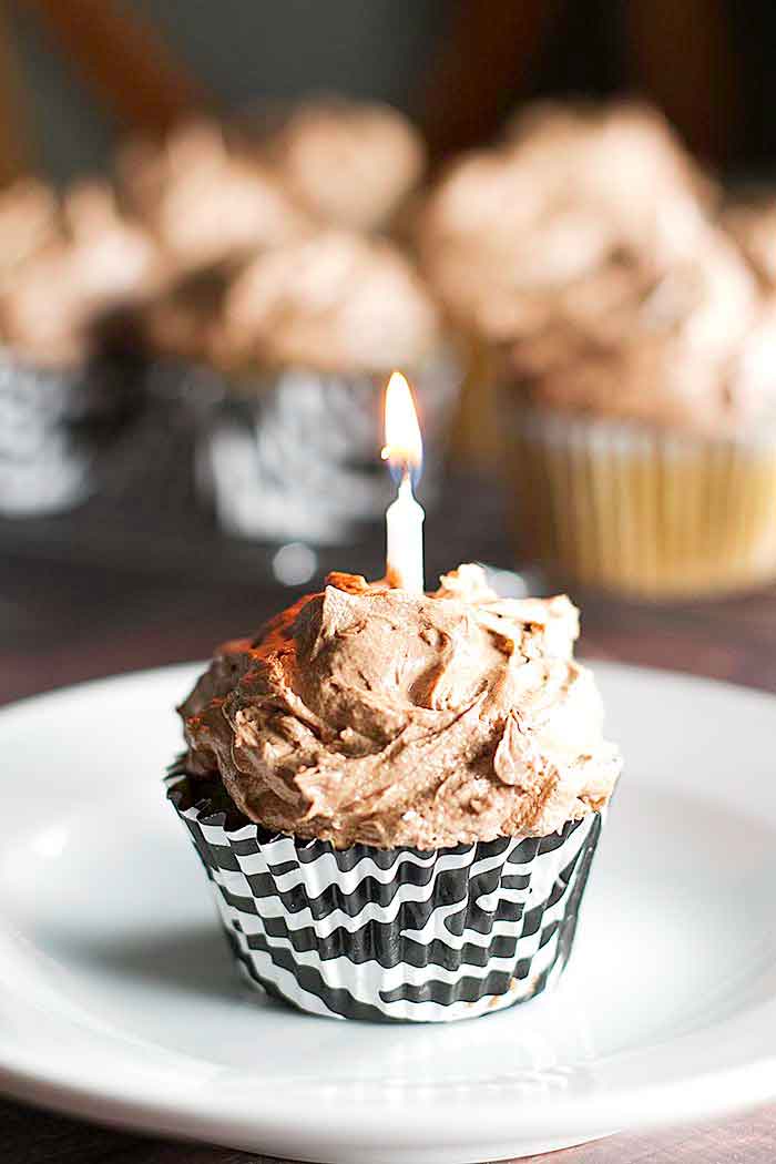one coffee cupcake with chocolate buttercream frosting with a birthday candle