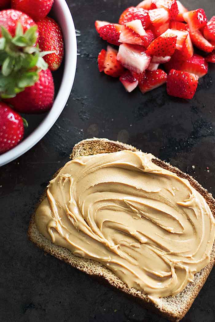 toast with peanut butter and diced strawberries next to it