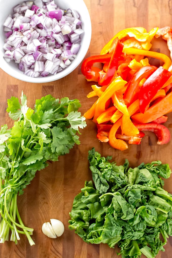 Vegetables for three bean chili: red onion, cilantro, bell pepper, and fresh spinach