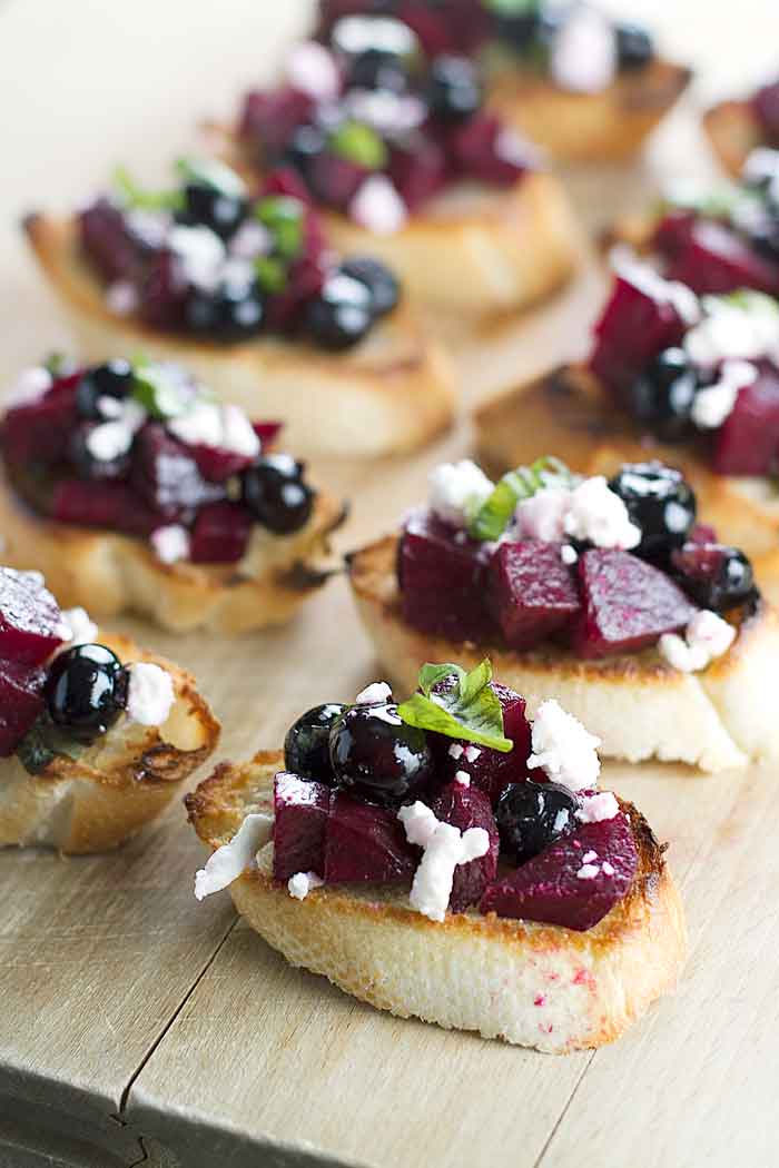 beet and blueberry bruschetta lined up on a cutting board