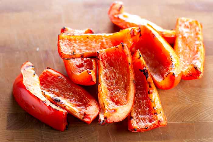 Sliced grilled red bell peppers on a cutting board