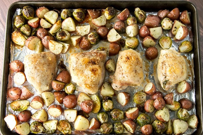overhead photo of roasted chicken, brussels sprouts, and potatoes on a sheet pan