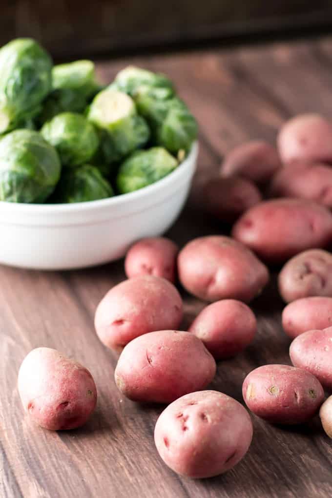 Photo of red potatoes with a bowl of brussels sprouts in the background