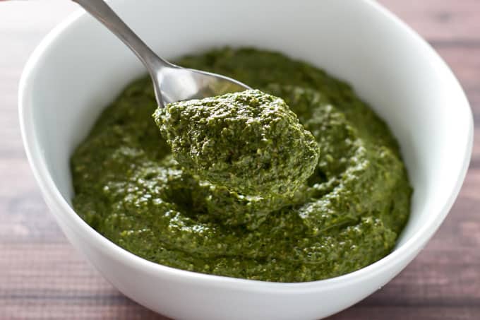 beet tops pesto in a white bowl with a spoon