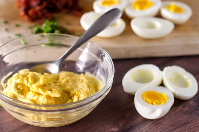 a bowl of egg filling with halved hard boiled eggs next to it.