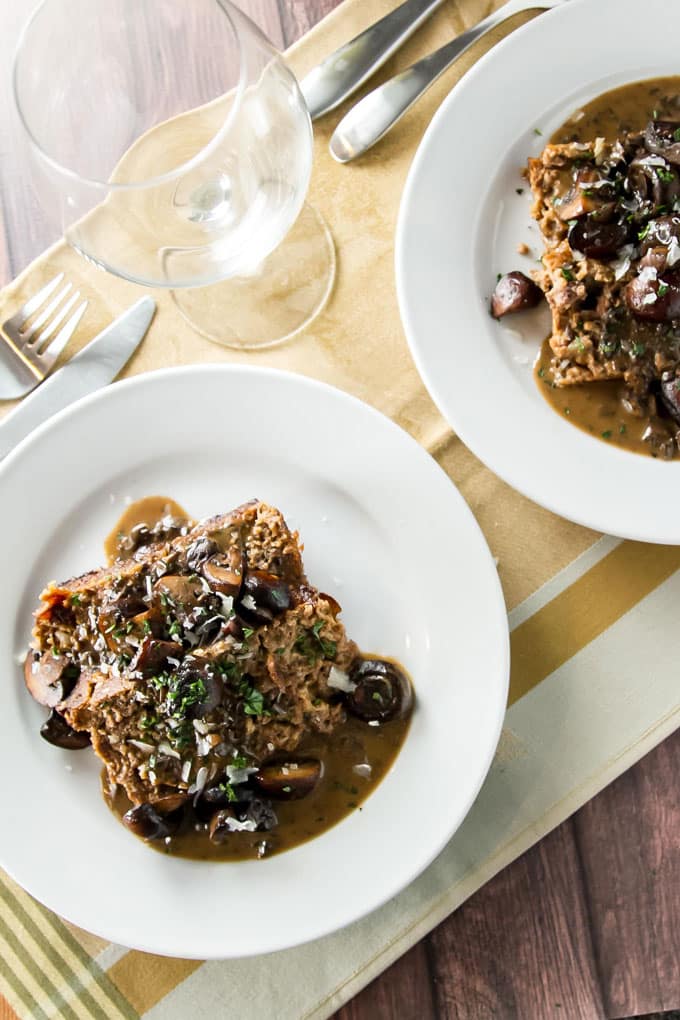 two plates with meatloaf topped with balsamic mushroom sauce