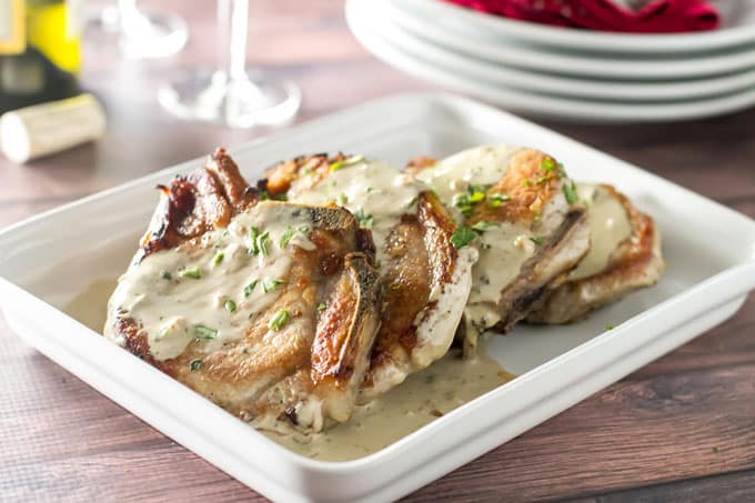 Oven roasted pork chops with a creamy mustard sauce on a white serving dish