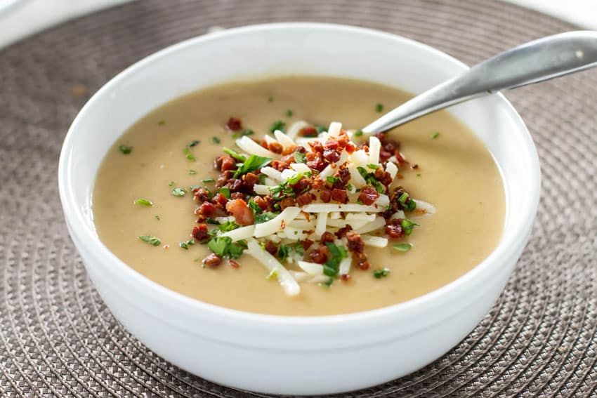 Potato Soup with Crispy Pancetta in a white bowl with a spoon