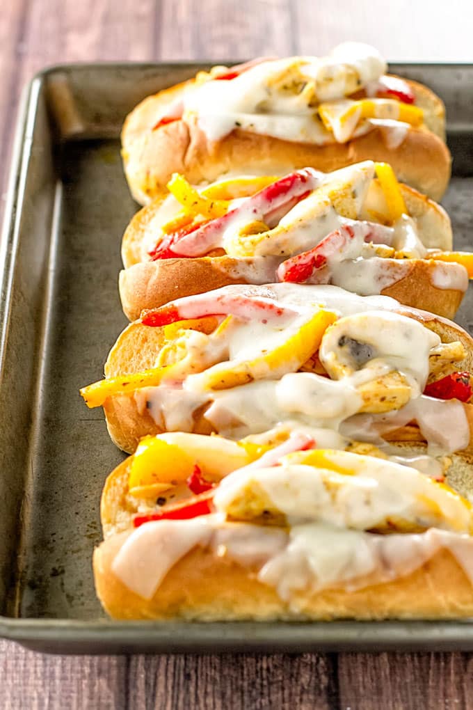 Chicken and peppers on soft rolls on a baking dish