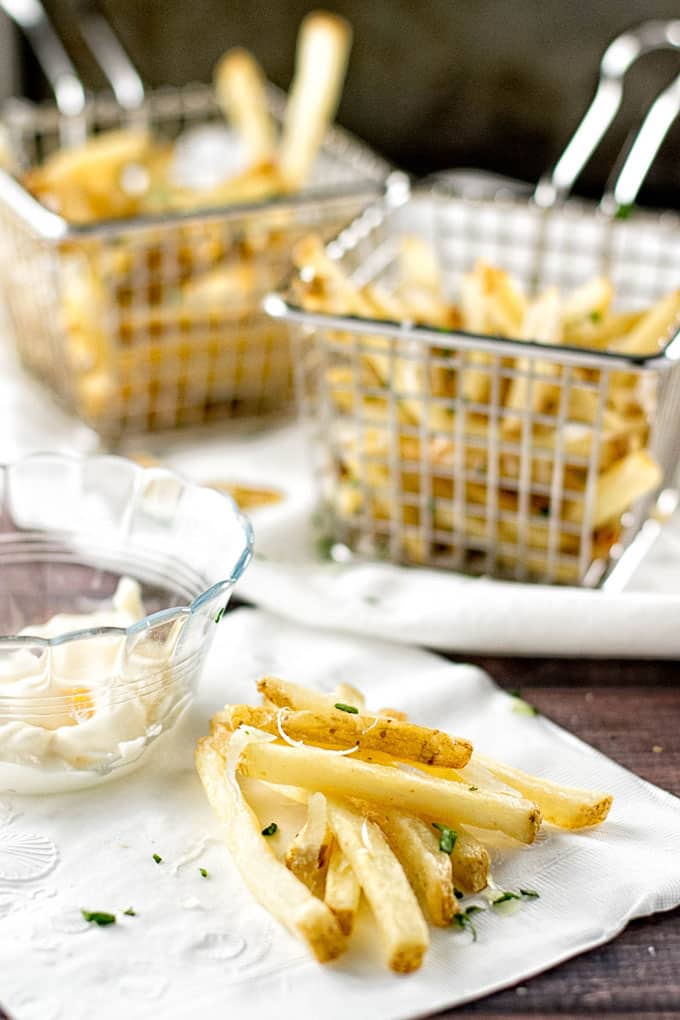 photo of french fries on a napkin with more in baskets in the background