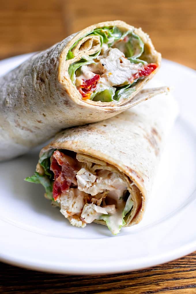 two sun-dried tomato chicken salad wraps stacked on a plate