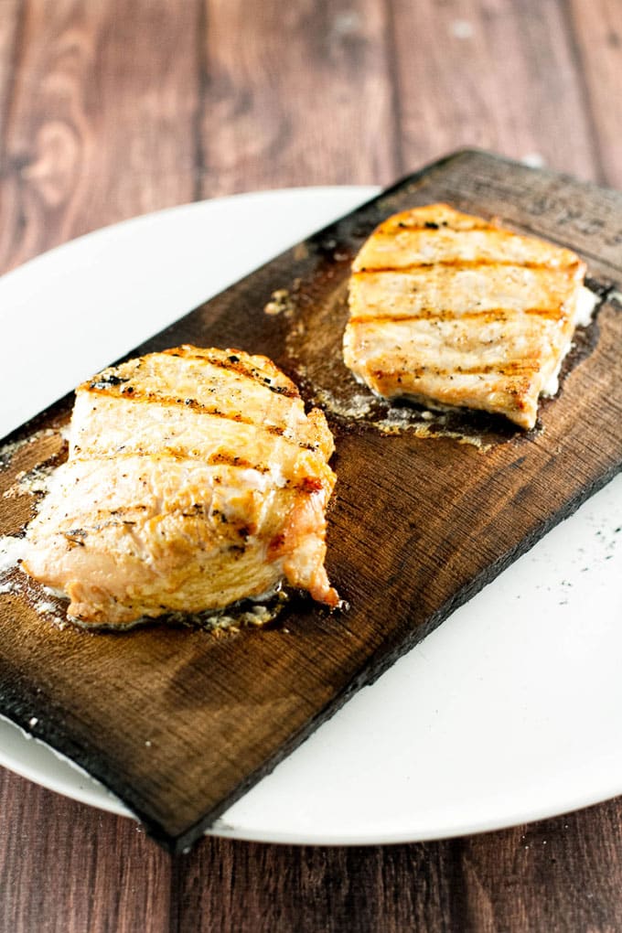 two grilled pork chops on a cedar plank