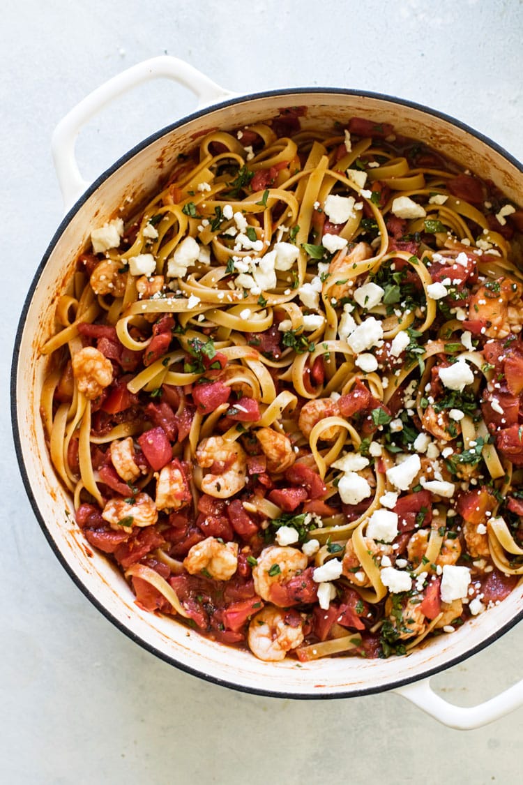Overhead photo of a pan of shrimp fettuccine with tomatoes and feta