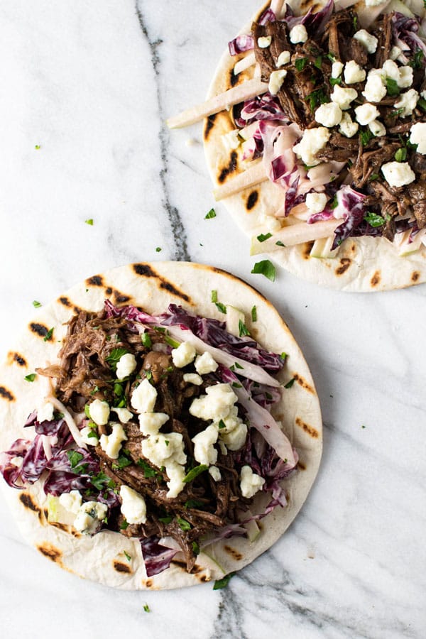 Two Short Rib Tacos with Radicchio Apple Slaw on a marble board