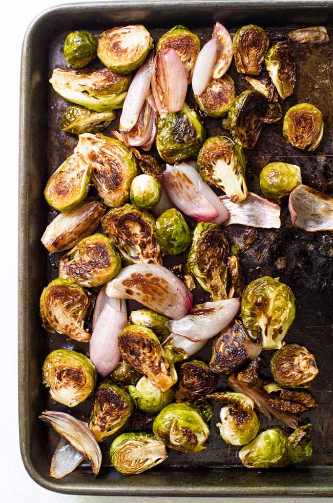 Roasted brussels sprouts and shallots on a baking sheet