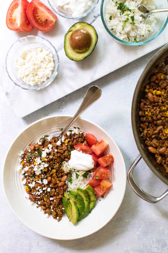 ground turkey taco bowl with tomatoes, avocado, cheese, and rice