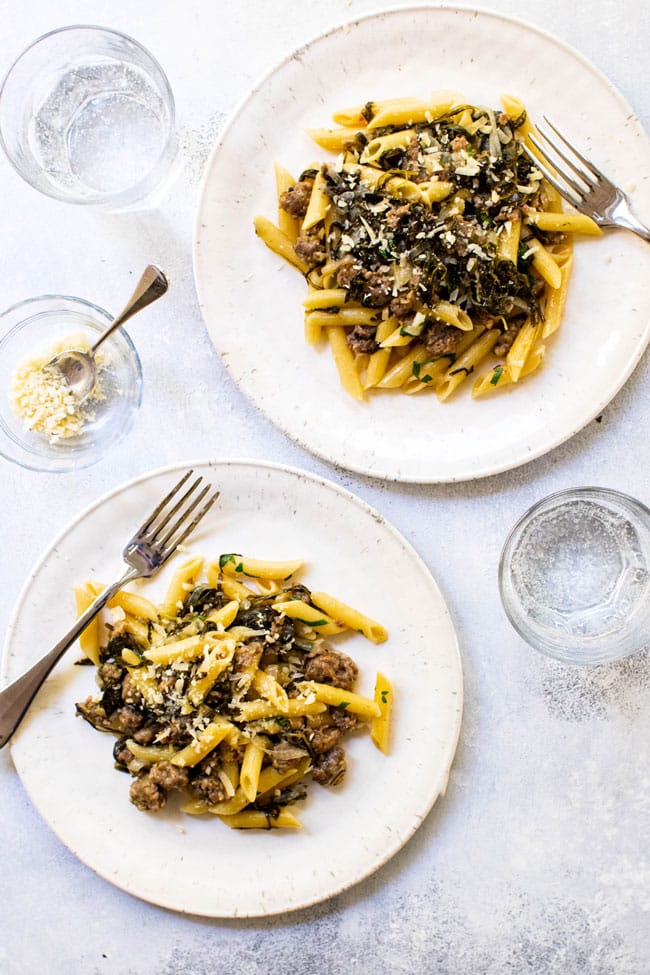 One-pot pasta with sausage and arugula on two plates