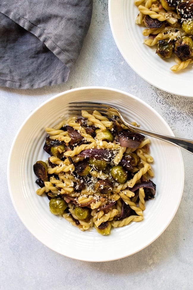 Roasted vegetable pasta in a bowl with a fork.