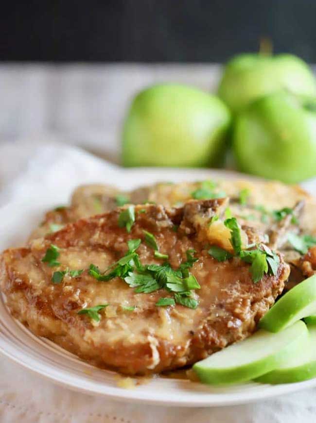 crock pot pork chops with apples on a plate with fresh apple slices