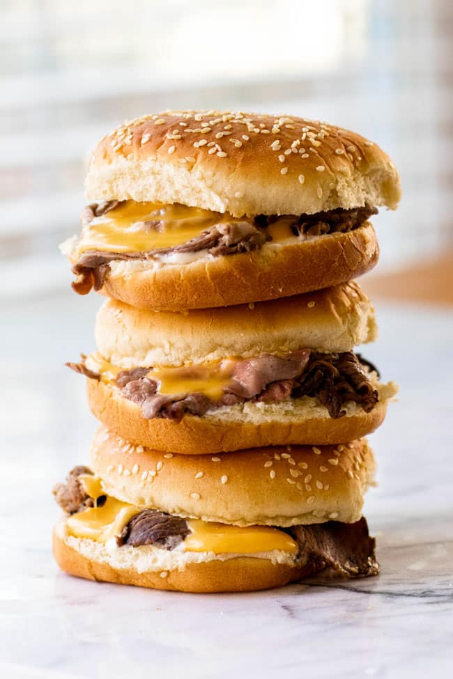 A stack of three hot roast beef sandwiches with cheddar cheese sauce