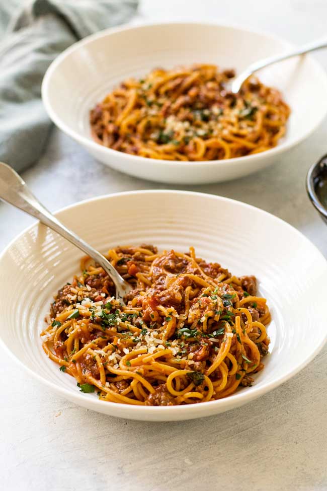 Two bowls of spaghetti bolognese with sun-dried tomatoes