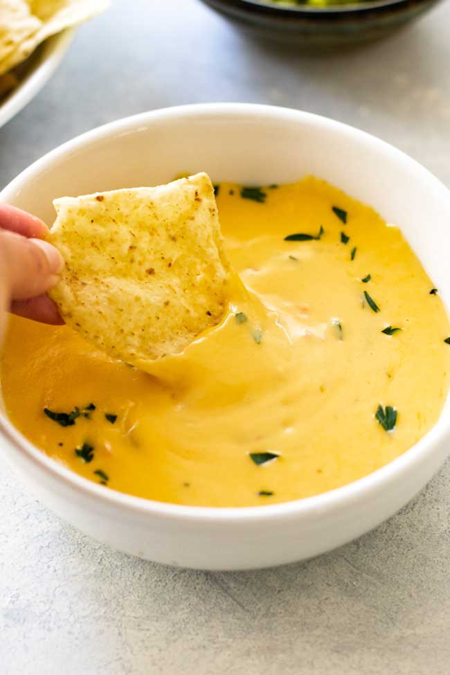 a bowl of cheese dip with a tortilla chip