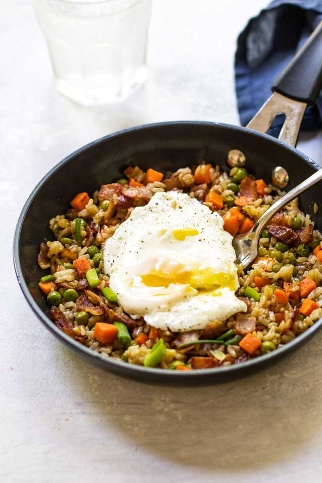 bacon fried rice in a black skillet with an egg on top