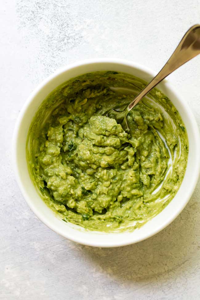 homemade guacamole in a white bowl used to garnish salsa verde taco soup