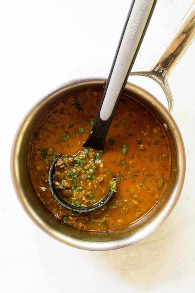 salsa verde taco soup in a saucepan with a ladle