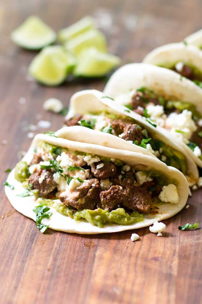 beef tacos on a cutting board with lime wedges