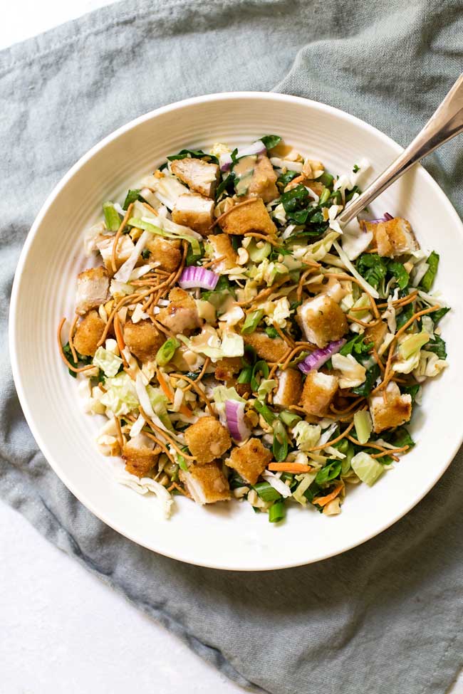 crispy chicken salad in a white bowl on a green napkin