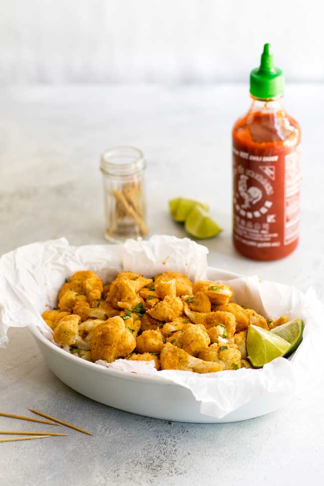 photo of a dish with sriracha-lime cauliflower bites with a bottle of sriracha in the background