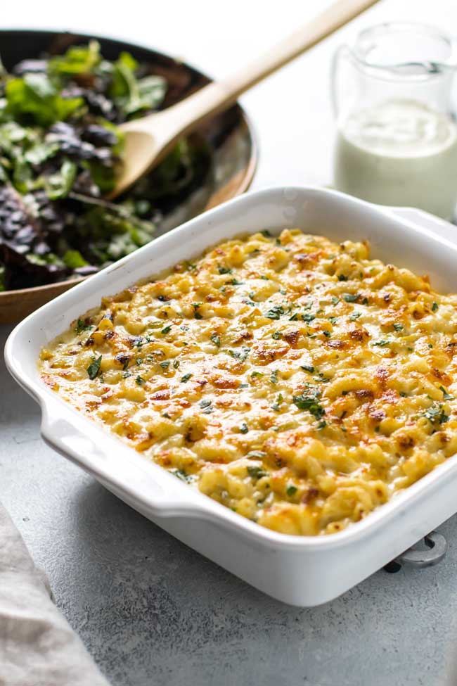 photo of green chile macaroni and cheese in a baking dish with a salad in the background