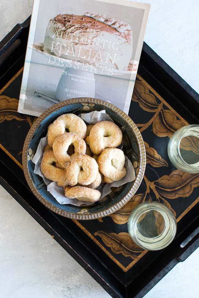 overhead photo of a tray with cookies, glasses of wine, and a cookbook