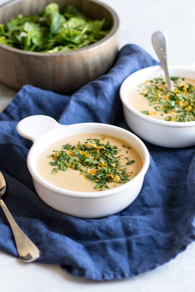 photo of two bowls of soup with a bowl of salad in the background
